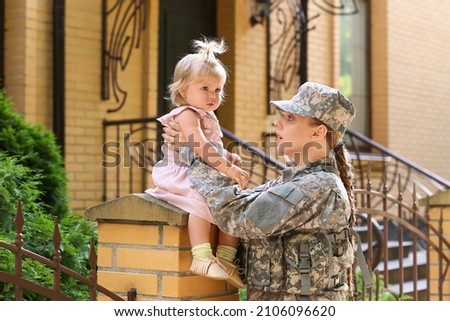 Cute baby girl with her military mother outdoors
