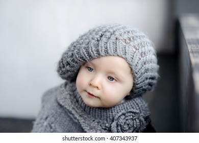 Cute Baby Girl In Knitted Beret Is Looking Away Seriously