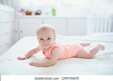 Cute baby girl lying on her tummy. Happy healthy kid at home in nursery