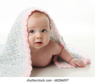 Cute Baby Girl Lying On Her Tummy With A Hand Crocheted Blanket Over Her Head