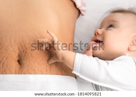 cute baby girl and mom's belly with stretch marks