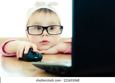 Cute baby with glasses looking into the laptop on a white background.