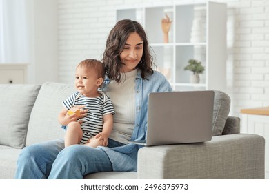 Cute baby and happy young mother working with laptop on maternity leave at home - Powered by Shutterstock