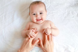 Cute Baby Holding Mother Hands While His Mom Making Belly And Body Massage For Him. Mixed Race Asian-German Infant Relaxing With Smiling Face.adorable Boy Massaging After Bathing.