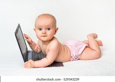 Cute baby with laptop computer on the white blanket background