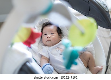 Cute baby laying in bouncer chair and looking at mobile