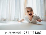 A cute baby lies on the bed, smiling and looking directly at the camera with bright, curious eyes. Their joyful expression captures a moment of pure happiness and innocence.