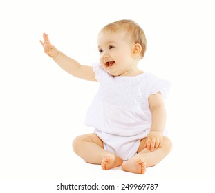 Cute baby looking up sitting on the floor greeting waving his hand on white background