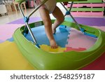 Cute baby making first steps with toy walker at home. Close up shot of babies feet while using the toy walker.