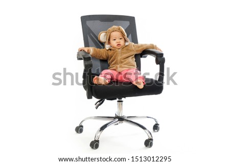 The cute baby in monkey clothes is sitting in the office chair playing           