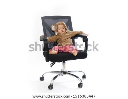 The cute baby in monkey clothes is sitting in the office chair playing           