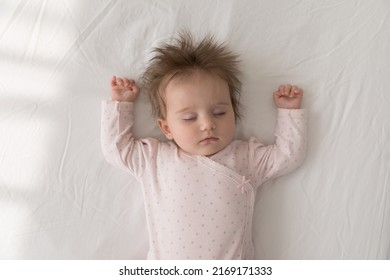 Cute Baby In Pink Comfort Bodysuit And Dry Diaper Sleeping On Bed With Arms Raised And Eyes Closed Looks Carefree Feels Peaceful, Top View. Sweet Babyhood, Healthy Day Nap For Newborn Growth Concept