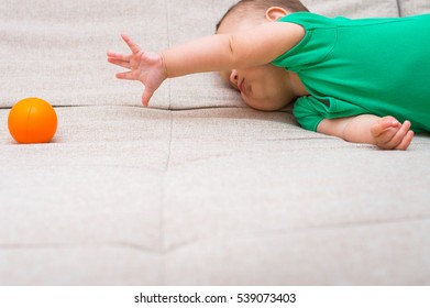 Cute Baby Playing With An Orange Ball