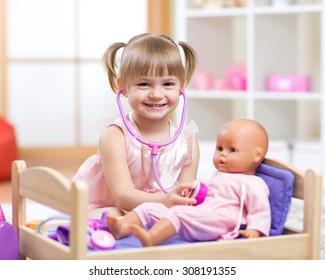 Cute Baby Plays In Doctor With Toy Doll And Stethoscope