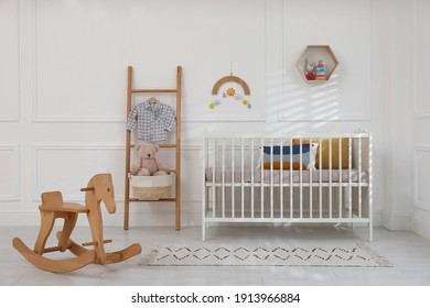 Cute baby room interior with comfortable crib and wooden rocking horse - Powered by Shutterstock