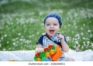 Cute Baby Is Sitting On A Linen Blanket And Playing With Colored Educational Toys. Products For Children. Child Teething. Child Care.