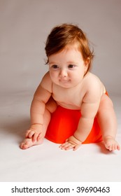 Cute Baby Sitting On The Orange Potty