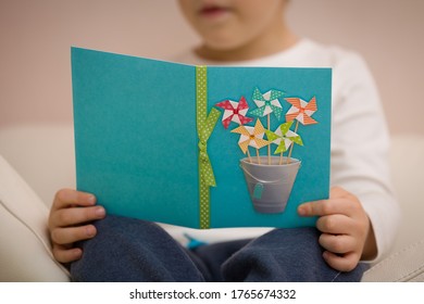 Cute Baby Sitting On The Sofa And Reading A Beautiful Greeting Card. Holiday Concept