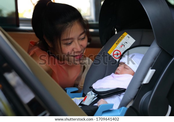 cute baby sleeping in\
car seat safety drive with mother, happy family road trip travel in\
vacation day