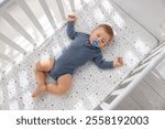 Cute baby sleeping in crib at home, top view