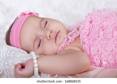 Cute Baby Is Sleeping, Lying Down On The Back Of A Pink Suit