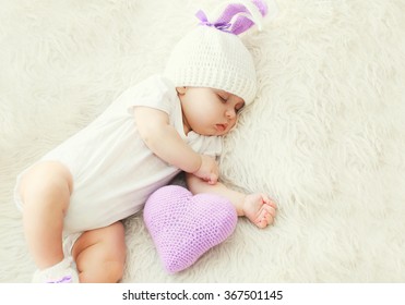 Cute baby sleeping on white bed at home with knitted pillow heart shape - Powered by Shutterstock