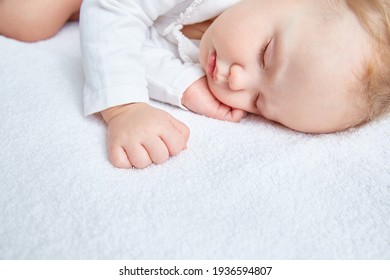 Cute Baby Sweetly Sleeps On White Bed Linen In White Clothes. Close-up. Beautiful Healthy Soft Skin, Long Eyelashes. Space For The Text.