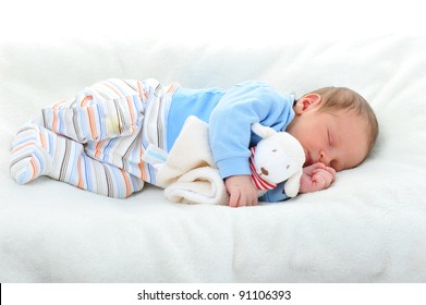 Cute Baby With Toy Sleeping On White Blanket