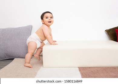 Cute Baby Wear White Diaper And Try To Stand  On White Background