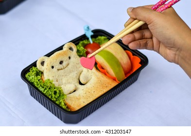 Cute Bear Bread with Apple, Tomato and Vegetables Bento. Pinching Heart Shaped Sugar with Chopstick - Powered by Shutterstock