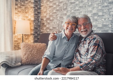 Cute and beautiful couple of old people smiling and looking at the camera having fun at home together. Portrait of seniors wearing eyeglasses sitting on sofa enjoying and relaxing. - Shutterstock ID 2217984117