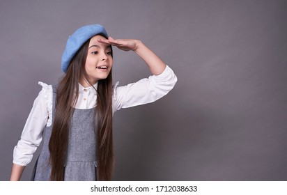 Cute beautiful emotional lady,a long-haired brunette,in a fashionable blue hat,takes a look at her suit and love, French girl in a white sweater and gray dress on a gray background.Copy Space. - Shutterstock ID 1712038633