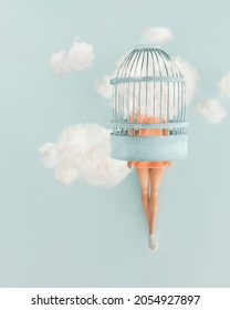 Cute beautiful female doll with head in clouds trapped in a blue cage hovering in space against pastel blue background. Minimal creative concept. Freedom, daydreaming and imagination note card idea.