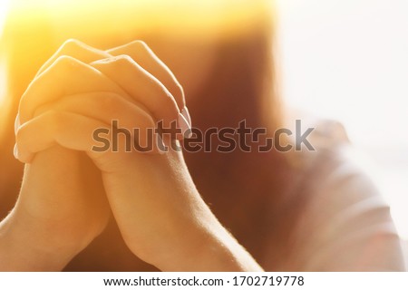 Cute beautiful girl folded her hands in prayer. A woman asks God for help