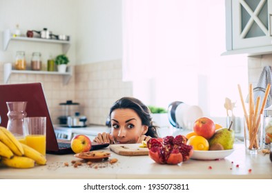 Cute Beautiful And Happy Young Brunette Woman In The Kitchen At Home Is Preparing Fruit Vegan Salad Or A Healthy Smoothie And Having Fun