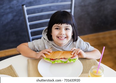 Cute Black Hair Little Girl Eating Sandwich At Home