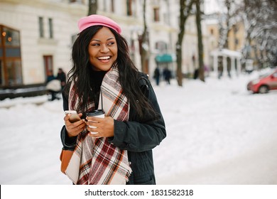 Cute black woman have fun in a city. Beautiful black girl in a pink beret. Stylish lady drinking a coffee. Famale use the phone - Powered by Shutterstock