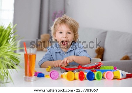 Cute blond child,  sweet boy, playing with play doh modeline at home, making different objects