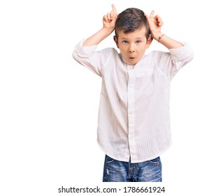 Cute Blond Kid Wearing Elegant Shirt Doing Funny Gesture With Finger Over Head As Bull Horns 