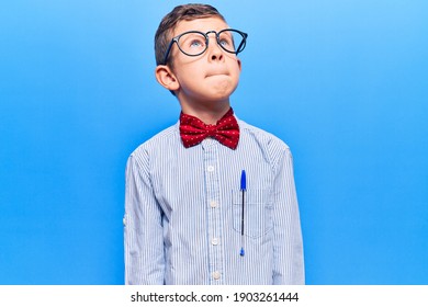 Cute blond kid wearing nerd bow tie and glasses smiling looking to the side and staring away thinking. 