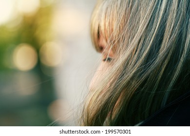 Cute blonde girl in profile against outdoor background. Outdoor profile portrait of a beautiful thoughtful young woman or teen girl with blond hair. Profile shot of attractive girl,outdoors, cpyspace