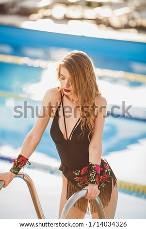 cute blonde girl in swimming suit next to the open air pool with ethnic accessories and jewellery,  soft focus, no brand, pin up posing