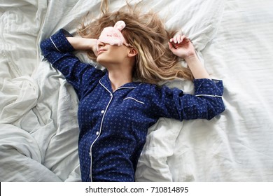 Cute Blonde In Her Bed In Blue Pajamas And Sleep Mask, Top View