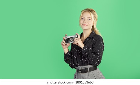 Cute blonde posing for the camera with a camera in hand, selective focus