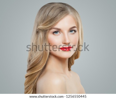 Cute blonde woman with long curly hair, clear skin and red lips makeup. Facial treatment, hair care and cosmetology concept