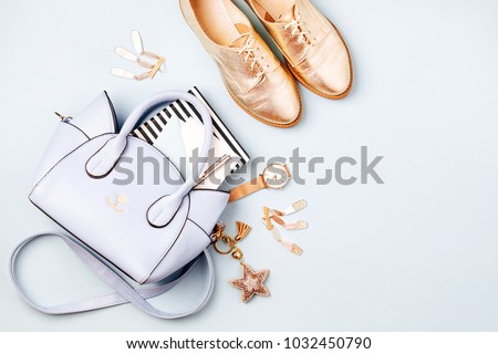 Cute blue ladies bag, stylish golden shoes and  feminine accessories . Flat lay, top view. Spring fashion concept in pastel colored 