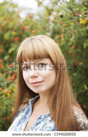Cute, blue-eyed. long-haired woman in the backdrop of the wild rose bush