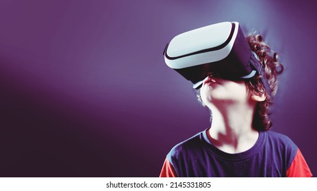 Cute boy with 3D goggles headset watching content on the metaverse cyberspace - isolated on shaded background with copy space - Powered by Shutterstock