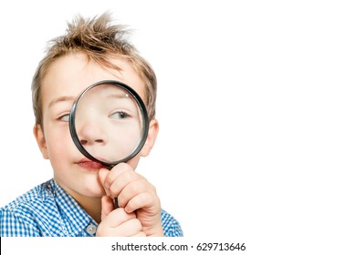 Cute boy in a blue shirt looking through a magnifying glass on a white background. Isolated