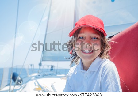 Cute boy captain on board of sailing yacht on summer cruise. Travel adventure, yachting with child on family vacation. Kid clothing in sailor style, nautical fashion.